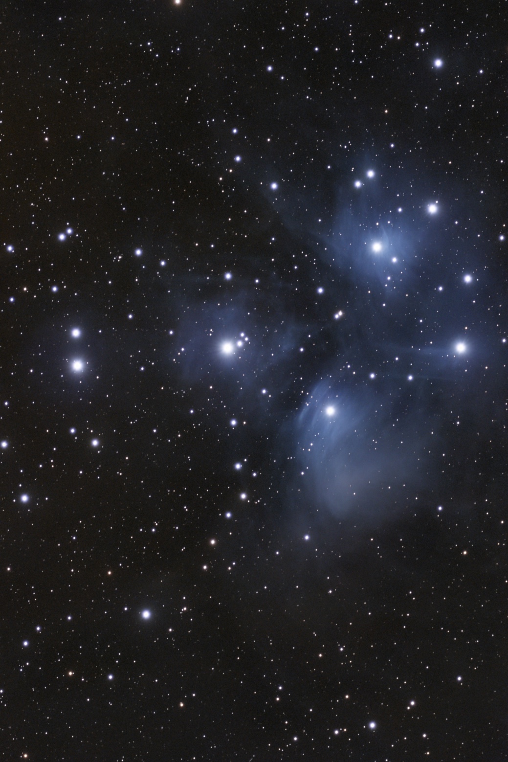 A starry night sky filled with numerous bright stars and scattered clouds of interstellar gas and dust.